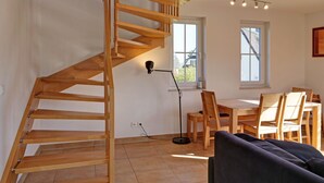 Et moderne interiør med en trappe i træ, et spiseområde med stole og et bord.