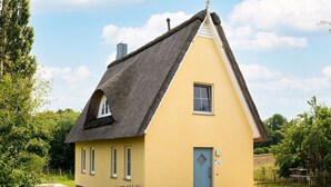 Et gult hus med stråtækt tag, et lille vindue og en dør.