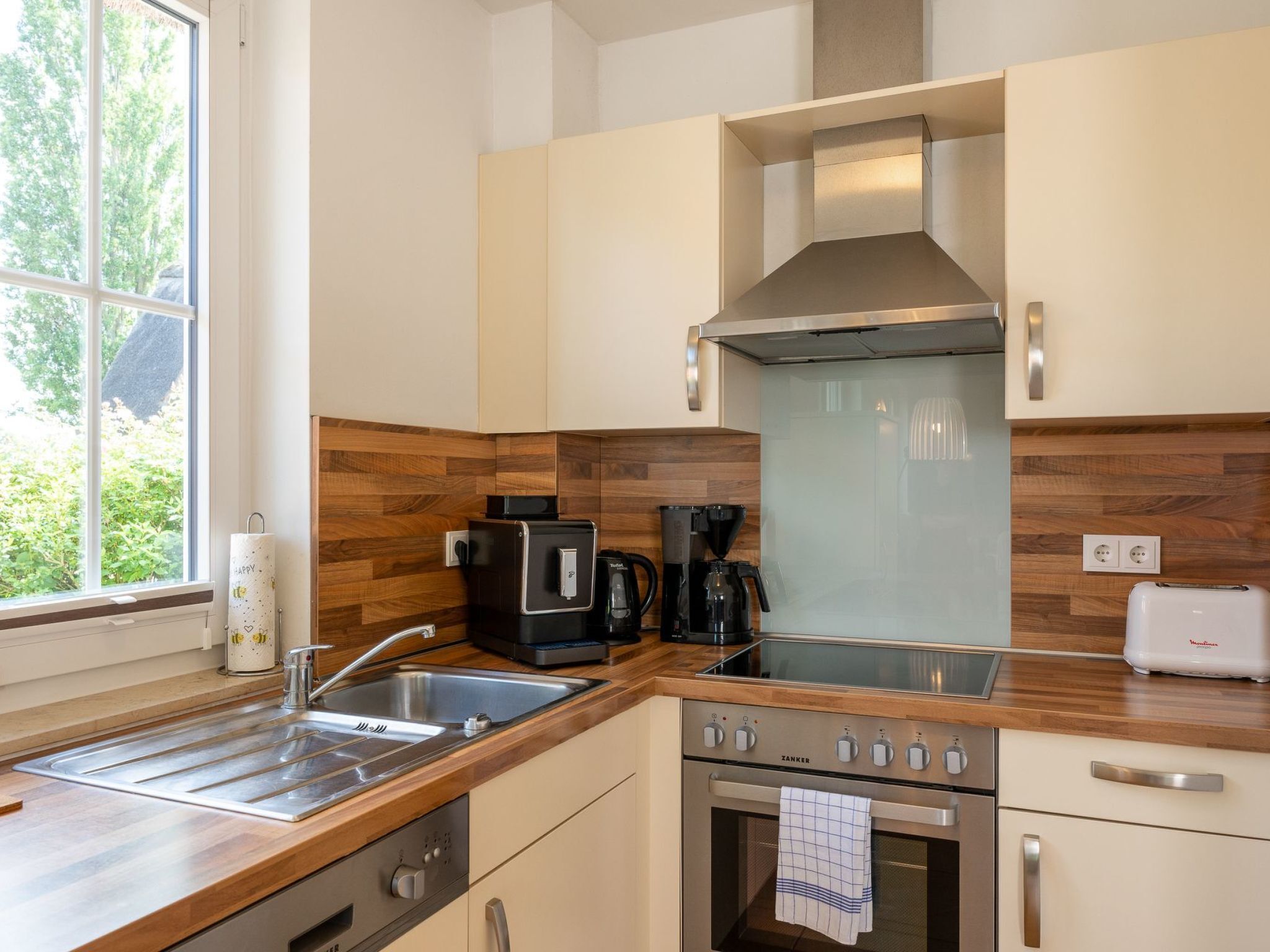 A modern kitchen with a stainless steel sink, a coffee maker, and a stove.