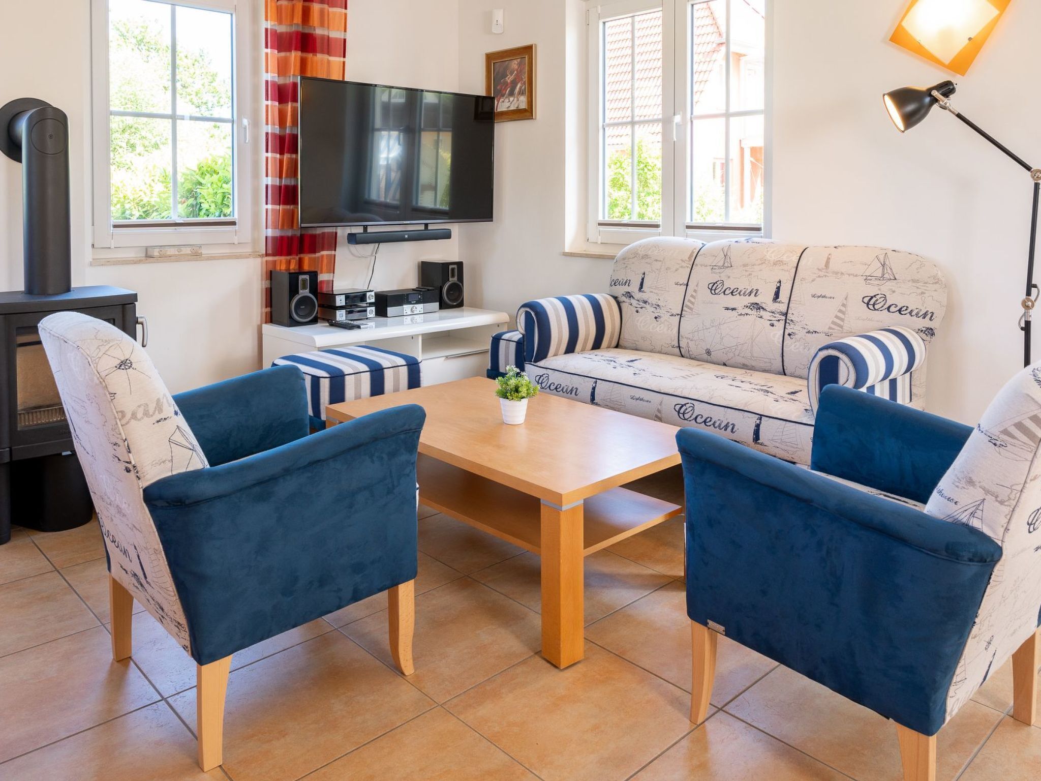 A living room with a sofa, two armchairs, a TV, a fireplace, and a window with curtains.