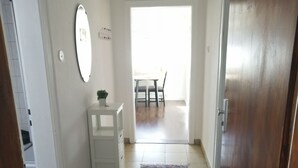 Un pasillo con un armario blanco, una alfombra y una puerta que da a un comedor.