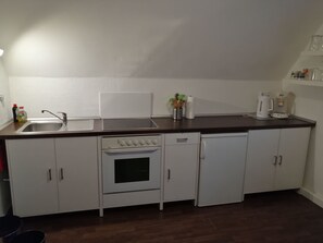 Een koelkast, een oven, kookgerei, borden en bestek