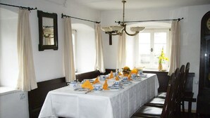 A dining room with a long table set for a meal, featuring blue and white plates, yellow napkins, and a vase with flowers. - Ferienhaus by Interhome (Schernfeld)