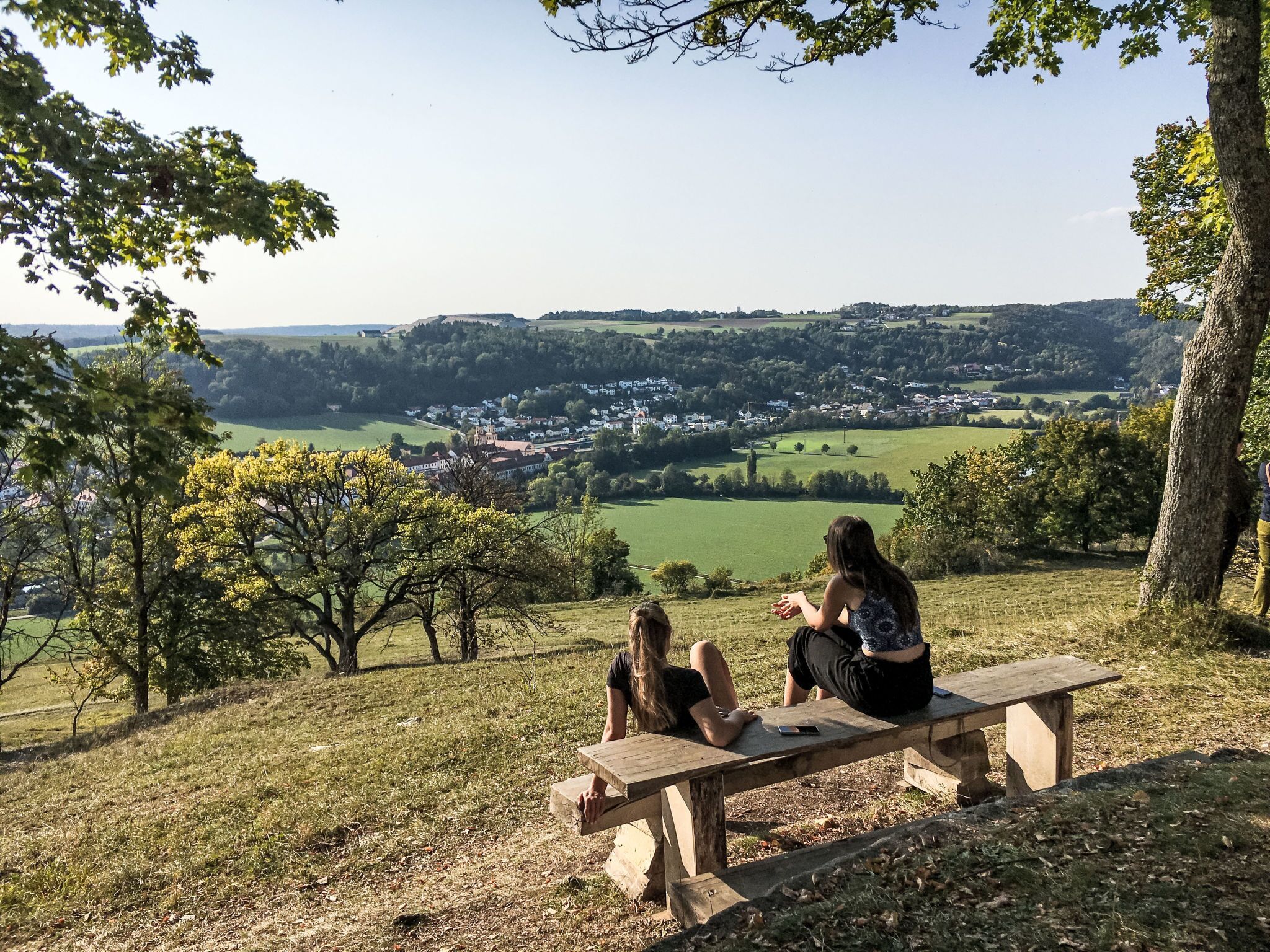 A picnic table in a grassy area with a view of a town in the distance.