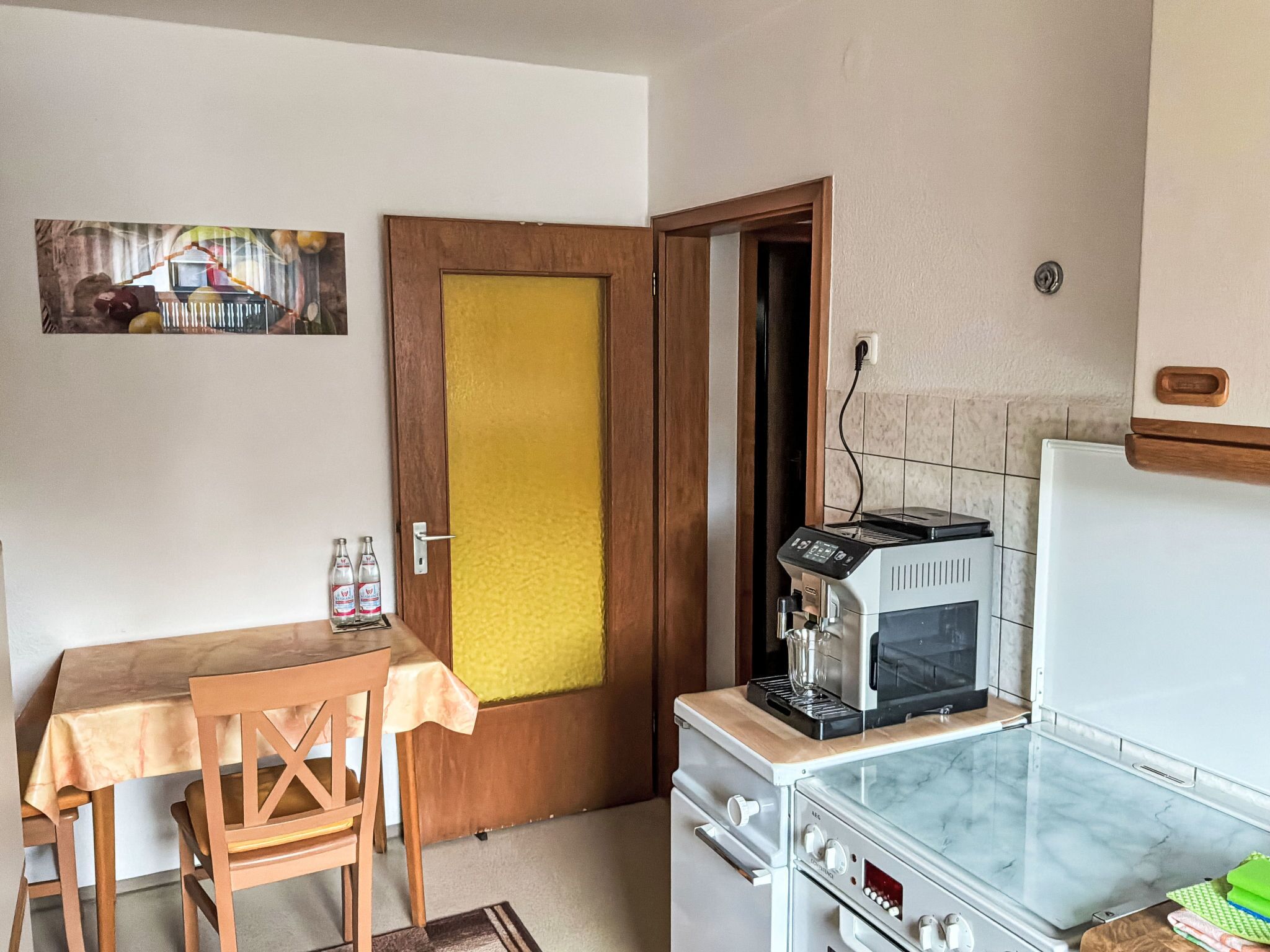 A compact kitchen with a microwave, stove, and a small dining table with a chair.