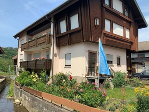 A two-story building with a balcony, a flag, and a garden with various flowers. - Freistehendes Ferienhaus mit Südbalkon by Interhome (Marktrodach)