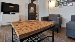 Ein modernes Wohnzimmer mit Couchtisch aus Holz, grauem Sofa und schwarzem Kamin.