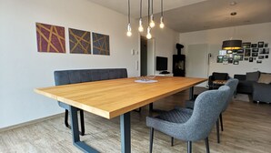 Ein moderner Essbereich mit einem Holztisch, blauen Stühlen und hängenden Leuchten.