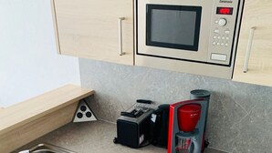 A compact kitchen with a built-in microwave, a coffee maker, and a toaster. - Charmantes Appartement in Lam by Interhome (Lam)