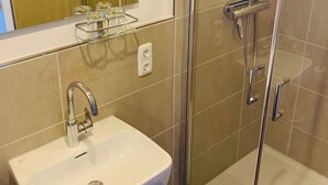 A modern bathroom with a glass-enclosed shower, a white sink, and a mirror above the sink. - Charmantes Appartement in Lam by Interhome (Lam)