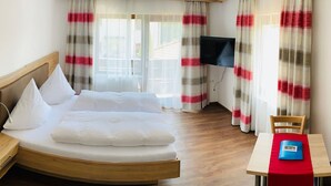 A hotel room with a bed, a TV, a dining table with a red tablecloth, and wooden flooring. - Charmantes Appartement in Lam by Interhome (Lam)