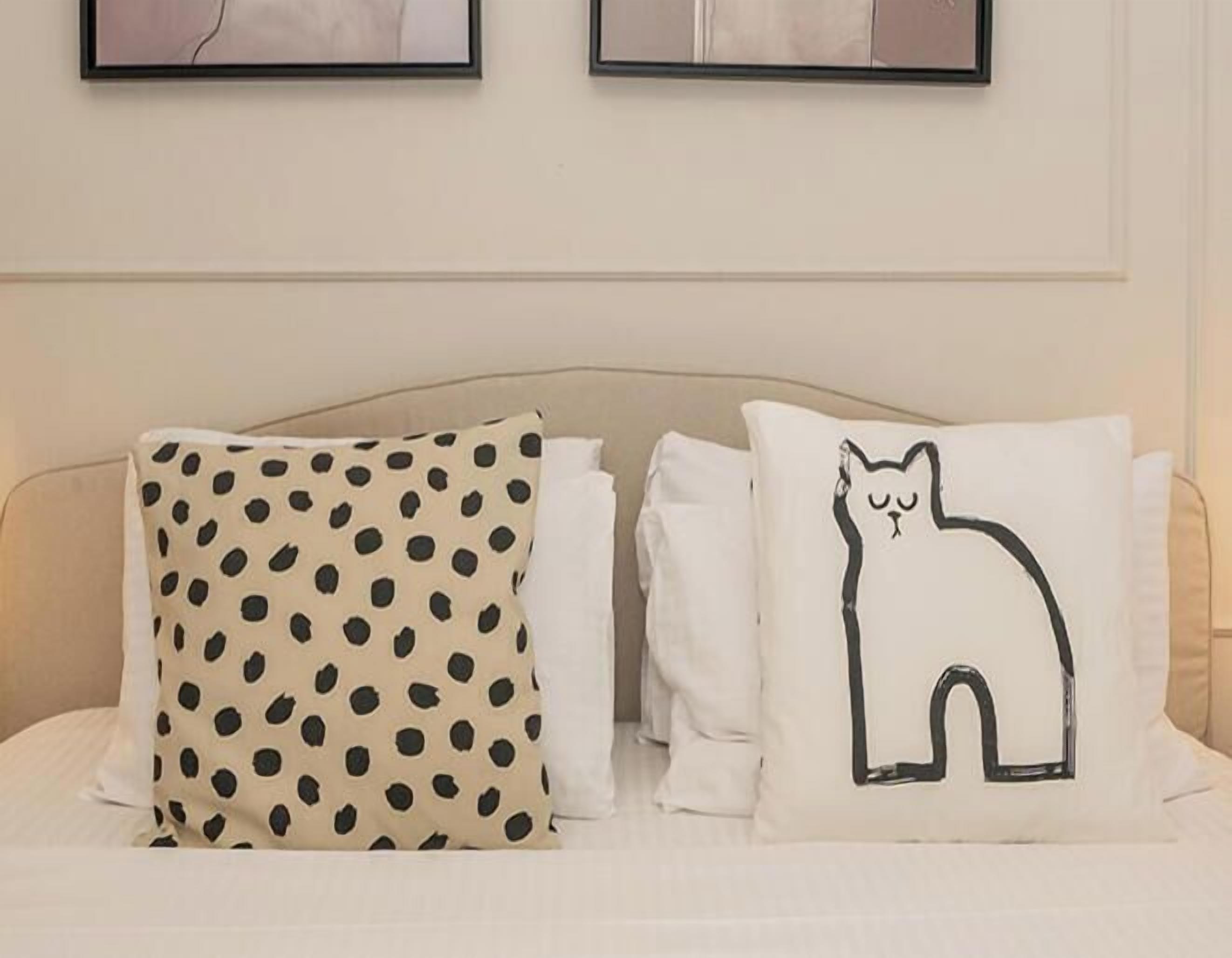 En säng med två kuddar, den ena med ett prickigt mönster och den andra med ett kattmotiv.