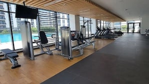 Et fitnessrum med træningsudstyr, store vinduer og loft af træ.