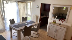 Un comedor con una mesa, sillas, un armario pequeño y un espejo.