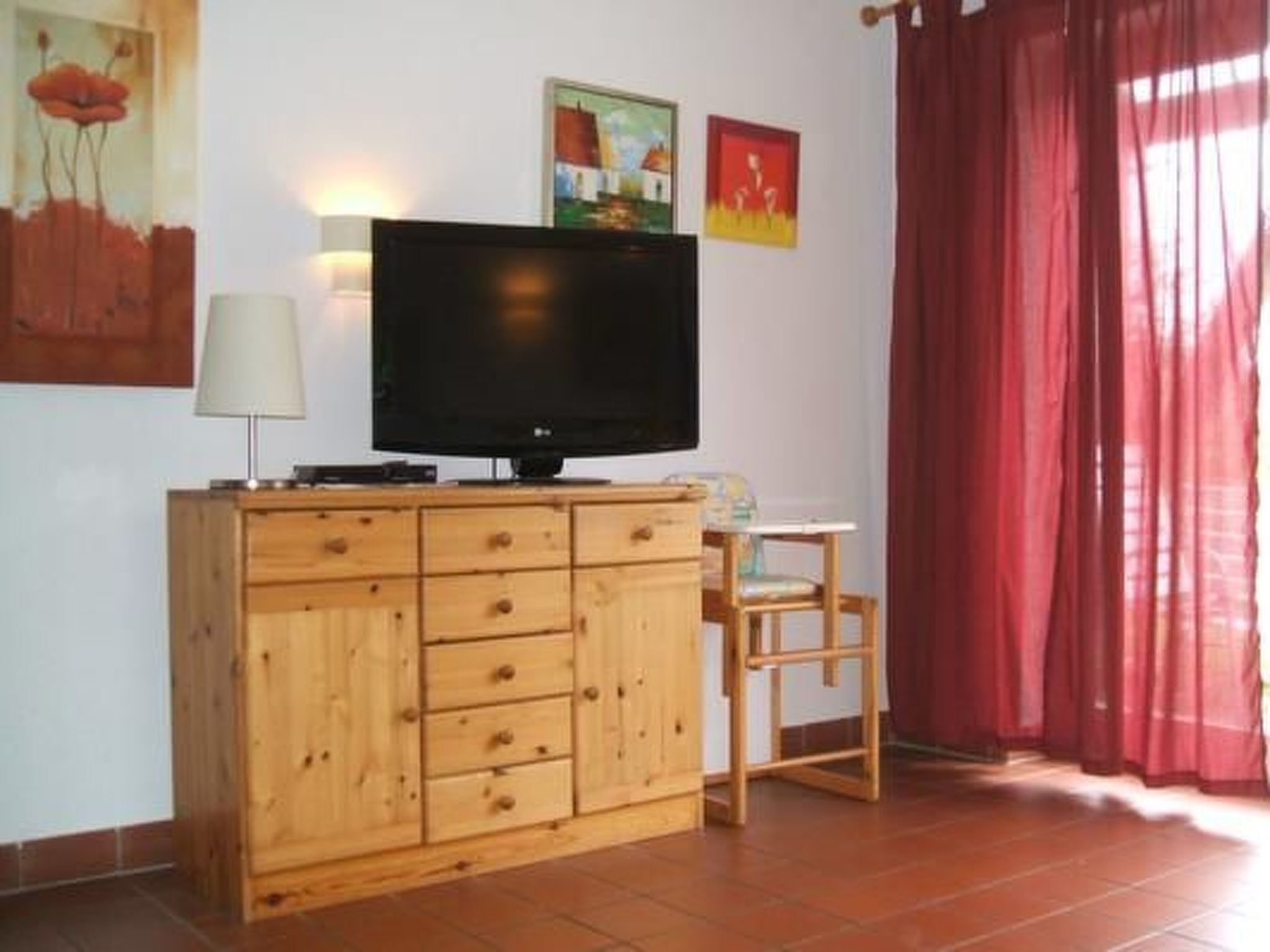 Une pièce comprenant un meuble en bois, une télévision, une petite table et une chaise.