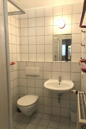 A small, tiled bathroom with a toilet, sink, and mirror. - in Zandt mit Garten, Terrasse und Grill by Interhome (Zandt)