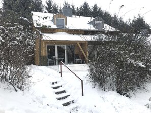 A wooden cabin with a covered porch and a staircase leading to the entrance. - in Zandt mit Garten, Terrasse und Grill by Interhome (Zandt)