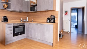 Une cuisine moderne avec des armoires grises, un plan de travail en bois et un four encastré. On y trouve également une machine à café et un four à micro-ondes, posés sur le plan de travail.