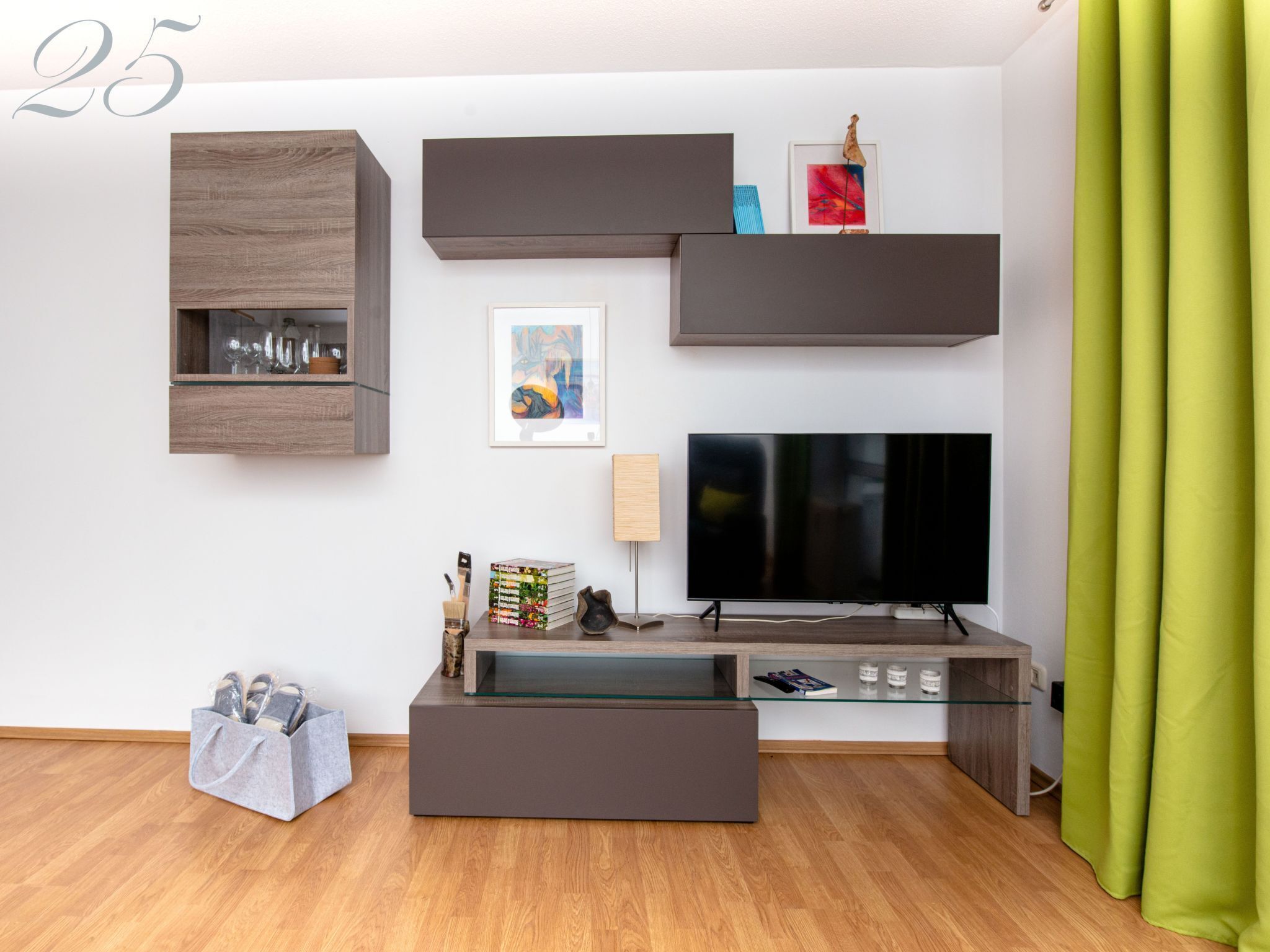 A modern living room with a flat-screen TV, built-in shelves, and a glass coffee table.