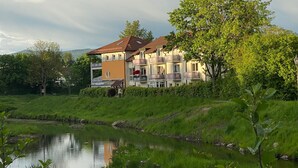 A multi-story residential building with balconies, a pond in the foreground, and lush greenery. - Ferienresidenz Am weißen Regen by Interhome (Bad Kötzting)
