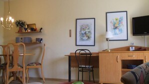 A dining area with a wooden table, chairs, and a chandelier. There are framed artworks on the wall and a television on the right. - Ferienresidenz Am weißen Regen by Interhome (Bad Kötzting)