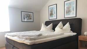 A neatly made bed with white bedding and pillows, a dark headboard, and two framed pictures on the wall. - Ferienresidenz Am weißen Regen by Interhome (Bad Kötzting)