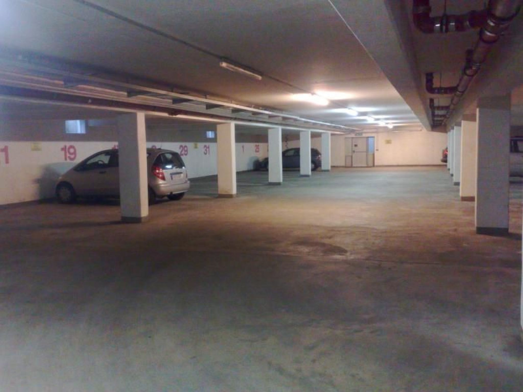 A multi-level parking garage with concrete pillars and numbered parking spaces.