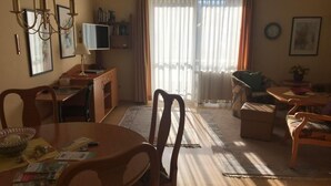 Un soggiorno con tavolo da pranzo, sedie, televisore e divano.