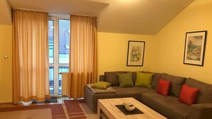 Un soggiorno con un divano marrone, un tavolino in legno e vista attraverso una porta in vetro.