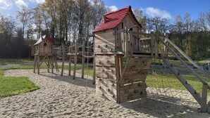 A playground with wooden climbing structures and slides. - Haus am See mit Fasssauna, Liegewiese und Grill by Interhome (Waldkirchen)