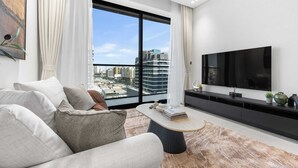 Een moderne woonkamer met een groot raam, een flatscreen televisie en een minimalistisch design.