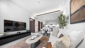 Een moderne woonkamer met een grote flatscreen televisie, een eethoek met een ronde tafel, en een keuken op de achtergrond.