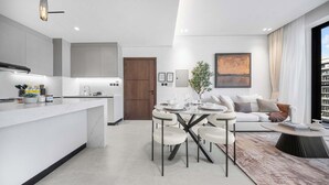 Een moderne keuken met een centraal eiland, een eethoek met een ronde tafel en stoelen, en een woonkamer met een bank en salontafel.