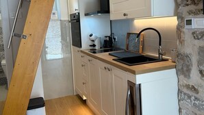 Una cocina moderna con armarios blancos, una escalera de madera, un muro de piedra y una lavadora.