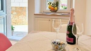 Una mesa de comedor con una botella de champán, dos copas de vino y un cuenco de caramelos de colores.