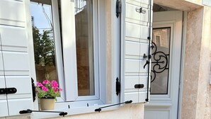 Un área de estar al aire libre con una mesa, sillas, una planta en maceta y una puerta con reja decorativa.