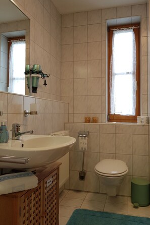 Ein Badezimmer mit Waschbecken, Toilette und einem Fenster mit Vorhängen.