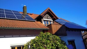 Een huis met zonnepanelen op het dak, een schoorsteen en een raam.
