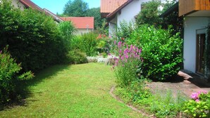 Een tuin met een pad dat naar een huis met een rood dak leidt.