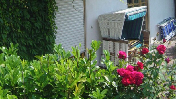 Een huis met een balkon, een overdekte veranda en een bloemen tuin.