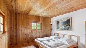 Una stanza con rivestimenti in legno, un letto, una finestra e un quadro appeso al muro.