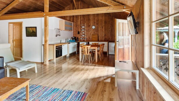Un ampio interno in legno con cucina, zona pranzo e una grande finestra.