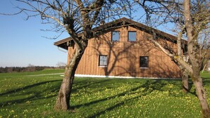 Una casa in legno con tetto spiovente, immersa in un prato fiorito di fiori gialli.