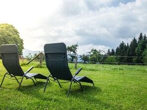 Two black lawn chairs on a grassy field with a fence and trees in the background. - am Riedl by Interhome (Siegsdorf)