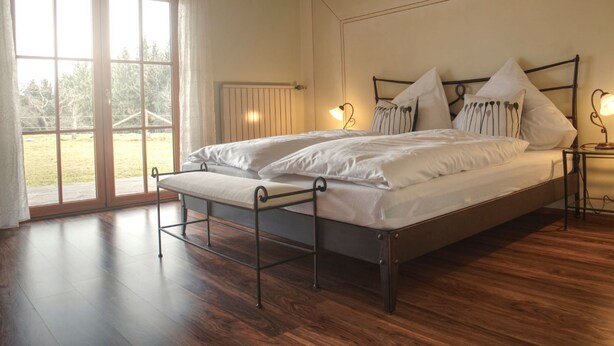 Una camera da letto con un letto grande, due comodini con lampade, una finestra con tende e vista sull'esterno.