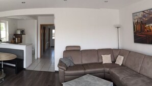 Een moderne woonkamer met een bruine leren modulaire bank, een kleine ronde tafel en een grijze salontafel.