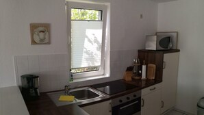 Een kleine keuken met een spoelbak, fornuis en koffiezetapparaat.