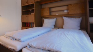 Quarto com duas camas, armários de madeira e estantes.