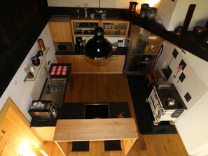 Eine kompakte Küche mit Holzschränken, einer zentralen Kochinsel und verschiedenen Geräten, darunter eine Kaffeemaschine und ein Wasserkocher.
