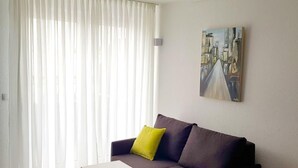 A modern living room with a sofa, a small table, and a painting on the wall. - Wohnung in Neckarwestheim by Interhome (Neckarwestheim)